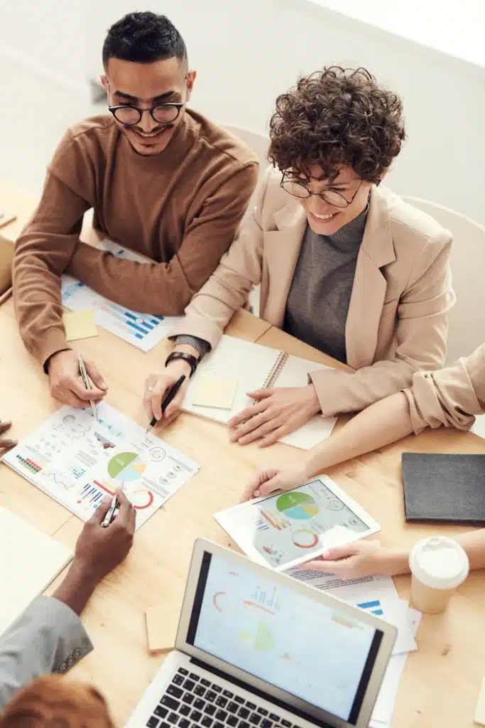 Fachleute sitzen zusammen und besprechen den Business Plan für eine Unternehmung Ein Businessplan Team von Fachleuten, die während eines Geschäftstreffens über Tabellen und Grafiken zusammenarbeiten.